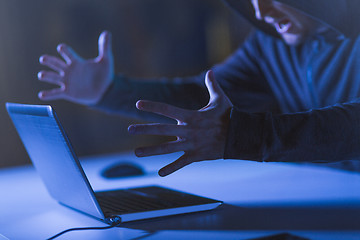 Image showing angry hacker with laptop shouting in dark room