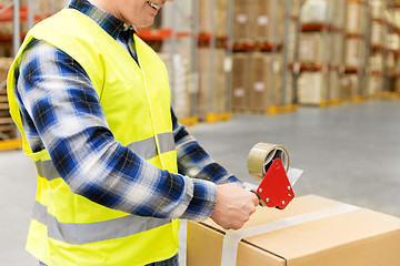 Image showing warehouse worker packing parcel with scotch tape