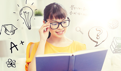 Image showing smiling young asian woman reading book at home