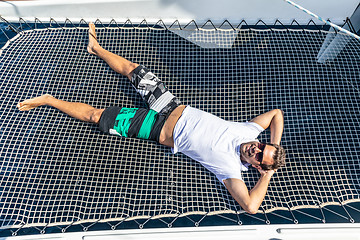 Image showing Sporty man relaxing on a luxury catamaran sailing boat.