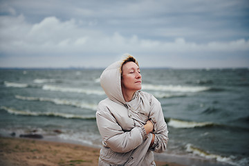 Image showing Adult woman in jacket standing near sea