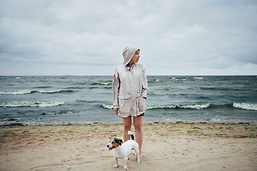 Image showing Young woman with dog looking away near sea