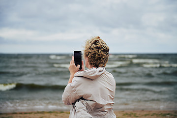 Image showing Unrecognizable female taking photo of stormy sea