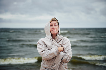 Image showing Adult woman in jacket standing near sea