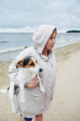 Image showing Woman in jacket holding dog on beach