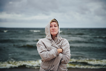 Image showing Adult woman in jacket standing near sea