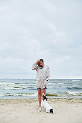 Image showing Woman in jacket looking at dog near sea