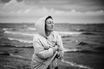 Image showing Adult woman wrapping in jacket near sea
