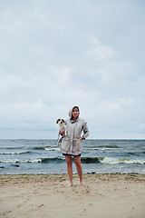 Image showing Young lady with dog near stormy sea