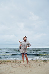 Image showing Young lady with dog near stormy sea