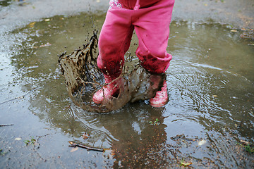 Image showing Child jumps in a dirty puddle