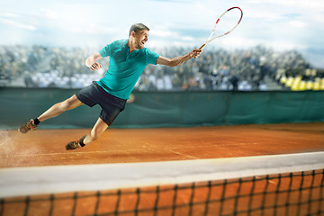 Image showing The one jumping player, caucasian fit man, playing tennis on the earthen court with spectators