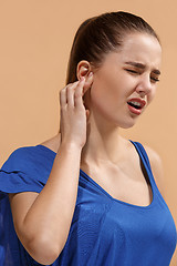 Image showing The Ear ache. The sad woman with headache or pain on a blue studio background.