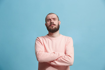 Image showing The serious businessman standing and looking at camera against blue background.