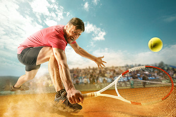 Image showing The one jumping player, caucasian fit man, playing tennis on the earthen court with spectators