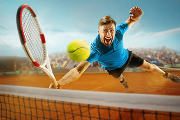 Image showing The one jumping player, caucasian fit man, playing tennis on the earthen court with spectators