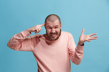 Image showing Beautiful male half-length portrait isolated on blue studio backgroud. The young emotional surprised man