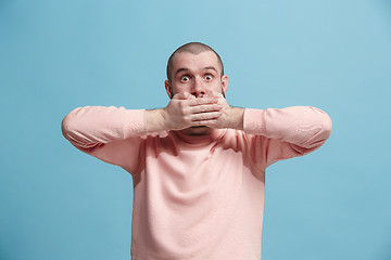 Image showing The young man whispering a secret behind her hand over blue background