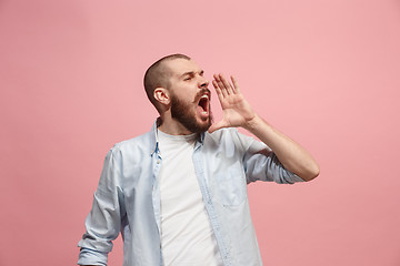 Image showing Isolated on pink young casual man shouting at studio