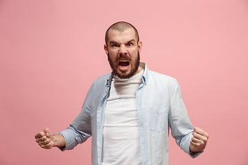 Image showing The young emotional angry man screaming on pink studio background