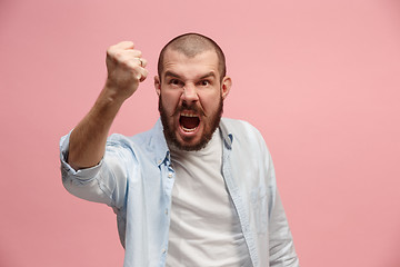 Image showing The young emotional angry man screaming on pink studio background