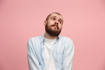 Image showing Let me think. Doubtful pensive man with thoughtful expression making choice against pink background