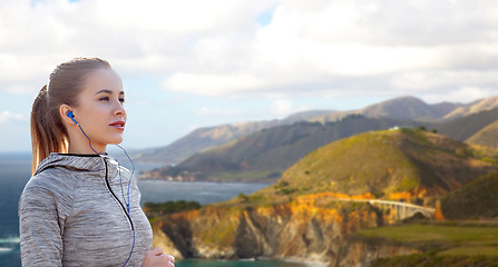 Image showing woman with earphones running over big sur coast