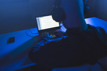 Image showing hacker with coding on laptop computer in dark room