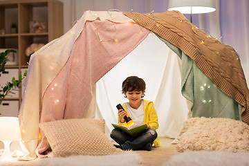 Image showing happy little boy reading book in kids tent at home