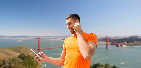 Image showing man with smartphone and earphones over golden gate