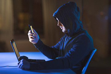 Image showing hacker with laptop and smartphone in dark room