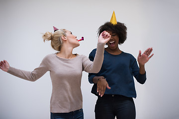 Image showing smiling women in party caps blowing to whistles