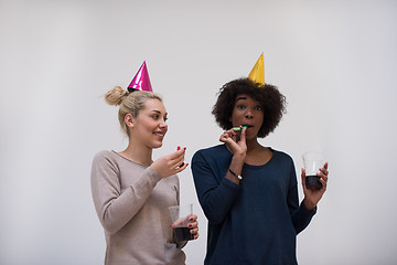 Image showing smiling women in party caps blowing to whistles