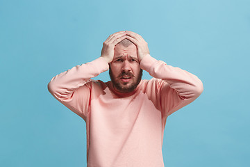 Image showing Man having headache. Isolated over blue background.