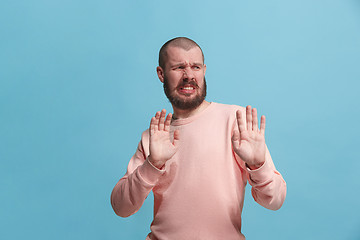 Image showing Young man with disgusted expression repulsing something, isolated on the pink