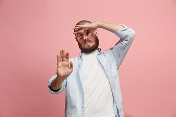 Image showing Young man with disgusted expression repulsing something, isolated on the pink