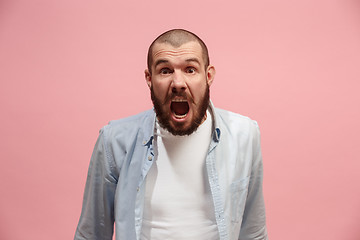 Image showing The young emotional angry man screaming on pink studio background