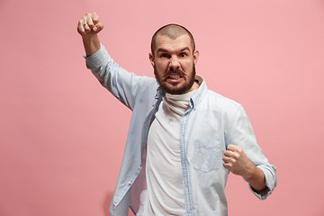 Image showing The young emotional angry man screaming on pink studio background