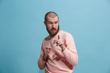 Image showing Suspiciont. Doubtful pensive man with thoughtful expression making choice against blue background