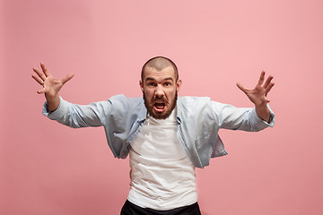 Image showing The young emotional angry man screaming on pink studio background