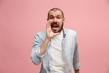 Image showing Isolated on pink young casual man shouting at studio