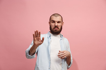 Image showing Young man with disgusted expression repulsing something, isolated on the pink