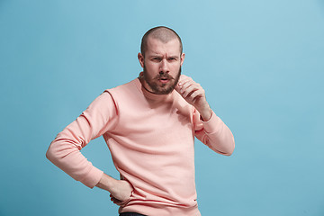 Image showing Suspiciont. Doubtful pensive man with thoughtful expression making choice against blue background