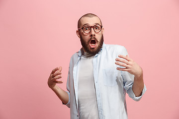 Image showing Beautiful male half-length portrait isolated on pink studio backgroud. The young emotional surprised man