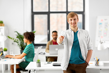 Image showing happy smiling man pointing finger at you at office