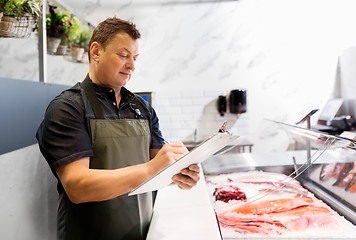 Image showing seller with clipboard selling seafood at fish shop