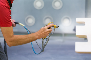 Image showing worker hand sprays urethane finish to board