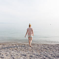 Image showing Happy Carefree Woman Enjoying Sunset Walk on White Pabbled Beach.
