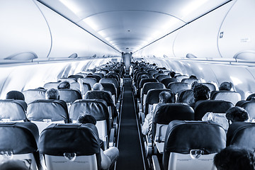 Image showing Interior of commercial airplane with passengers on their seats during flight.