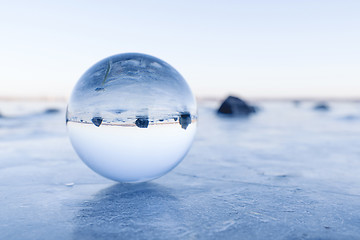 Image showing Black rocks in a glass orb on a frozen lake